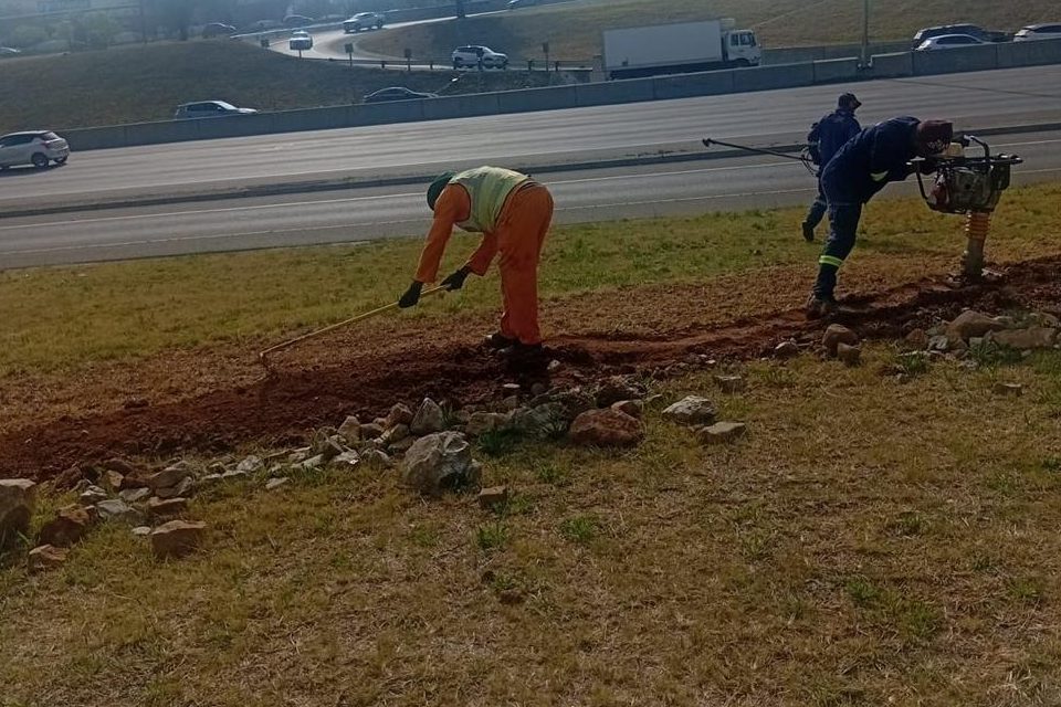Operatives levelling backfill and compacting a trench line beside a carriageway
