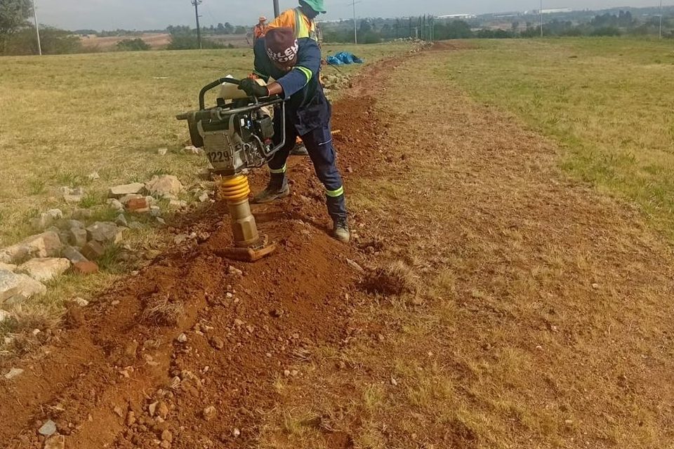 Operative compacting a backfilled trench with a mechanical rammer